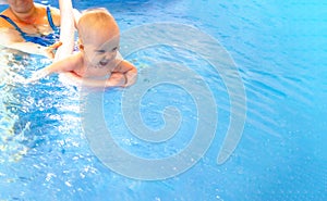 Adorable baby girl enjoying swimming in a pool with her mother early development class for infants teaching children to