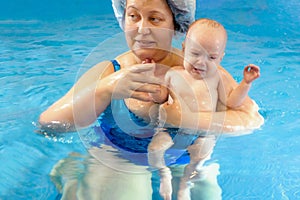 Adorable baby girl enjoying swimming in a pool with her mother early development class for infants teaching children to