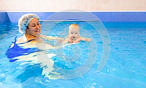 Adorable baby girl enjoying swimming in a pool with her mother early development class for infants teaching children to