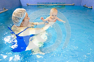 Adorable baby girl enjoying swimming in a pool with her mother early development class for infants teaching children to