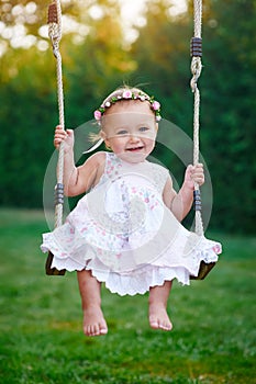 Adorable baby girl enjoying a swing ride on a playground in a park