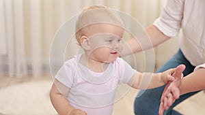 Adorable baby girl learning to walk toddler taking first steps with mother helping, walking at home. Child Smiling