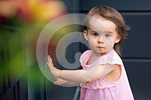 Adorable baby girl in pink summer dress on dark background