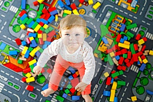 Adorable baby girl playing with educational toys . Happy healthy child having fun with colorful different wooden blocks