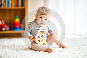 Adorable baby girl playing with educational toys . Happy healthy child having fun with colorful different wooden toy at