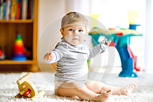 Adorable baby girl playing with educational toys . Happy healthy child having fun with colorful different wooden toy at