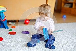 Adorable baby girl playing with educational toys . Happy healthy child having fun with colorful different wooden toy at