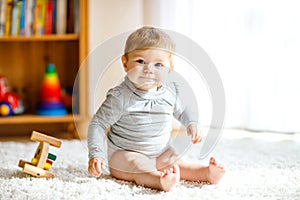 Adorable baby girl playing with educational toys . Happy healthy child having fun with colorful different wooden toy at