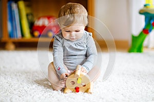 Adorable baby girl playing with educational toys . Happy healthy child having fun with colorful different wooden toy at