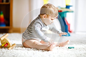 Adorable baby girl playing with educational toys . Happy healthy child having fun with colorful different wooden toy at