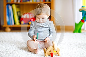 Adorable baby girl playing with educational toys . Happy healthy child having fun with colorful different wooden toy at