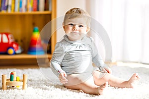 Adorable baby girl playing with educational toys . Happy healthy child having fun with colorful different wooden toy at