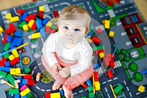 Adorable baby girl playing with educational toys in nursery