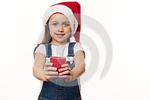 Adorable baby girl in Santa hat with a lit red candle in hands. Cute kid makes cherished wish for Christmas. Copy space