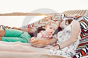 Adorable baby girl  shocked face, lying with her happy father and mother, young hipster couple relaxing with daughter in  a