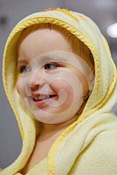 Adorable baby girl sitting under a hooded towel after bath