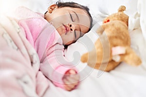 Adorable baby girl sleeping peacefully in bed with stuffed animal toy. Baby lying fast asleep on white bed with