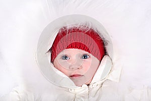 Adorable baby girl wearing red hat and white fur hood