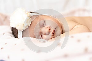 Adorable baby newborn with a headband sleeping on stomach