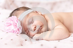 Adorable baby newborn with a headband sleeping on stomach