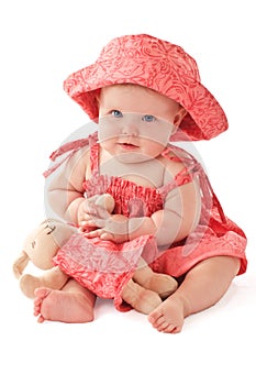 Adorable baby in pink dress plays with toy bunny