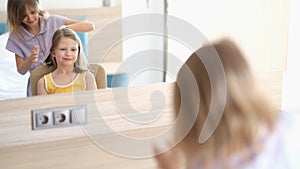 Adorable baby sisters using comb are sitting indoors