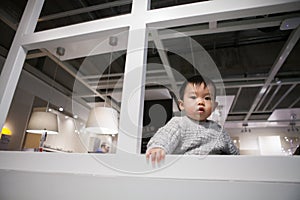 Adorable baby in sweater playing curiously in IKEA store