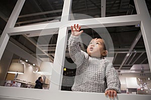 Adorable baby in sweater playing curiously in IKEA store