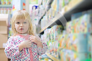 Adorable baby with toys on shelves in mall