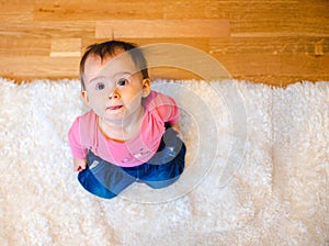 Adorable baby on white carpet looking up. Copy space on right
