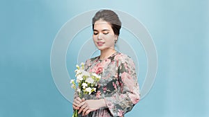 Adorable  beautiful woman holding bouquet of flowers isolated on blue background