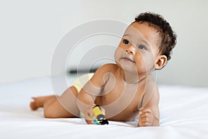 Adorable Black Baby Wearing Diaper Playing With Toy Car In Bed