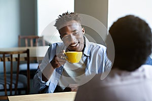 Adorable black couple chatting in coffee shop at lunchtime, having first date, starting romantic relationship