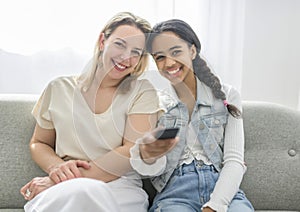 Adorable black twin teen girl with mother on studio white background holding remote control