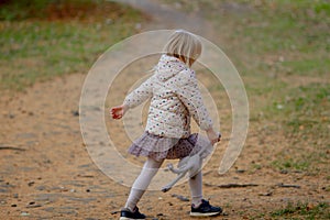 Adorable blond girl playing and jumping with her favorite toy grey cat on a beautiful autumn day.
