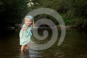 Adorable blond girl playing in river, exploration concept