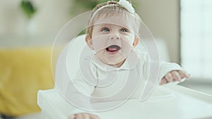 Adorable blonde baby smiling confident sitting on highchair at home