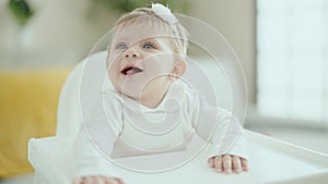 Adorable blonde baby smiling confident sitting on highchair at home