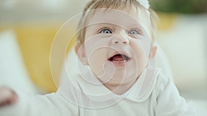 Adorable blonde baby smiling confident sitting on highchair at home