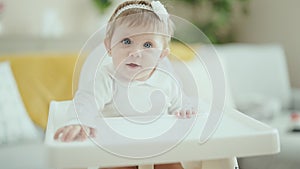 Adorable blonde baby smiling confident sitting on highchair at home