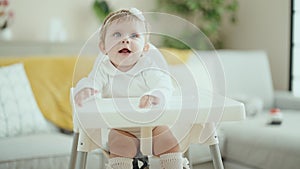 Adorable blonde baby smiling confident sitting on highchair at home