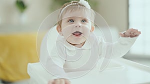 Adorable blonde baby smiling confident sitting on highchair at home