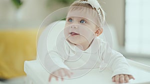 Adorable blonde baby smiling confident sitting on highchair at home