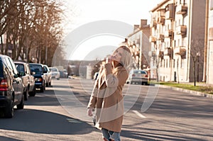 Adorable blonde girl walking alone on the road in old european city