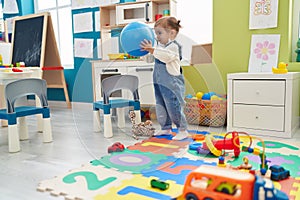 Adorable blonde toddler sitting on floor playing with truck at kindergarten