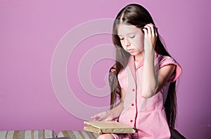 Adorable bookworm. Reading literature as hobby. Fiction and nonfiction. Cute small child reading book on violet