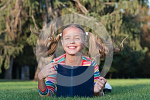 Adorable bookworm. Schoolgirl reading stories relaxing green lawn. Cute pupil enjoy reading. School time. Developing