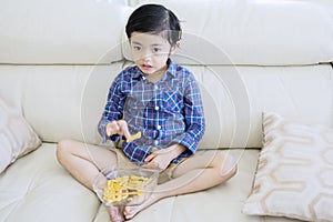 Adorable boy changing channel television on couch