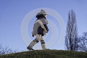 Adorable boy child runs around the hillside against the sky