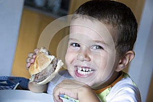 Adorable boy eating cheeseburger